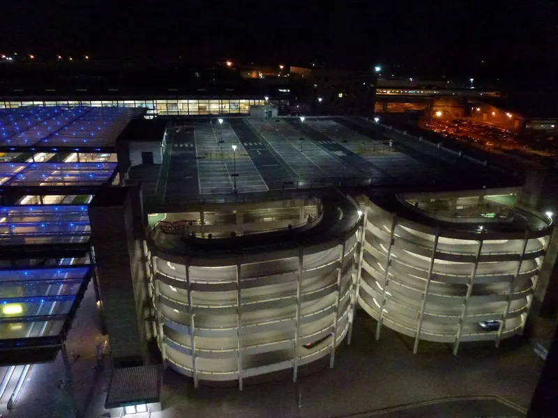 The curved multi-storey car park at Gatwick North Terminal lit up at night