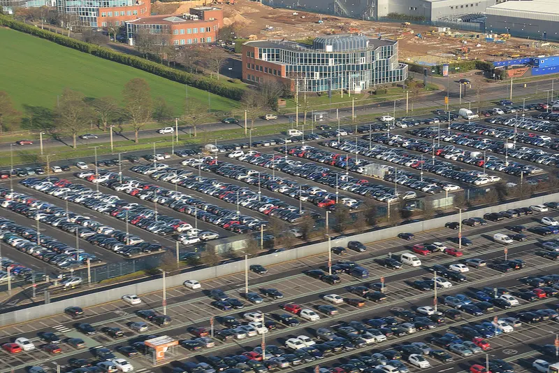 Rows of parked cars in a large surface car park at Heathrow Airport, seen from above
